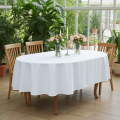 Biały obrus owalny 160×280 cm Lena Premium z tkaniny lnopodobnej i plamoodpornej na drewnianym stole w jasnej jadalni