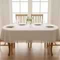 Obrus owalny beżowy plamoodporny z koronką – elegancki stół w jasnym wnętrzu przy oknie